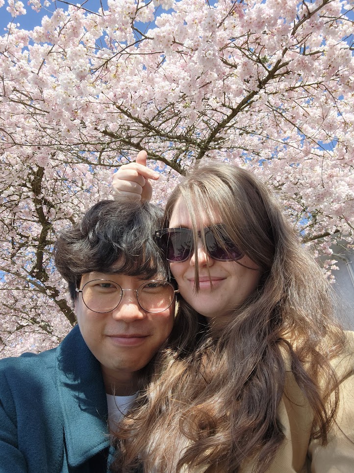The couple taking a photo beneath cherry blossoms