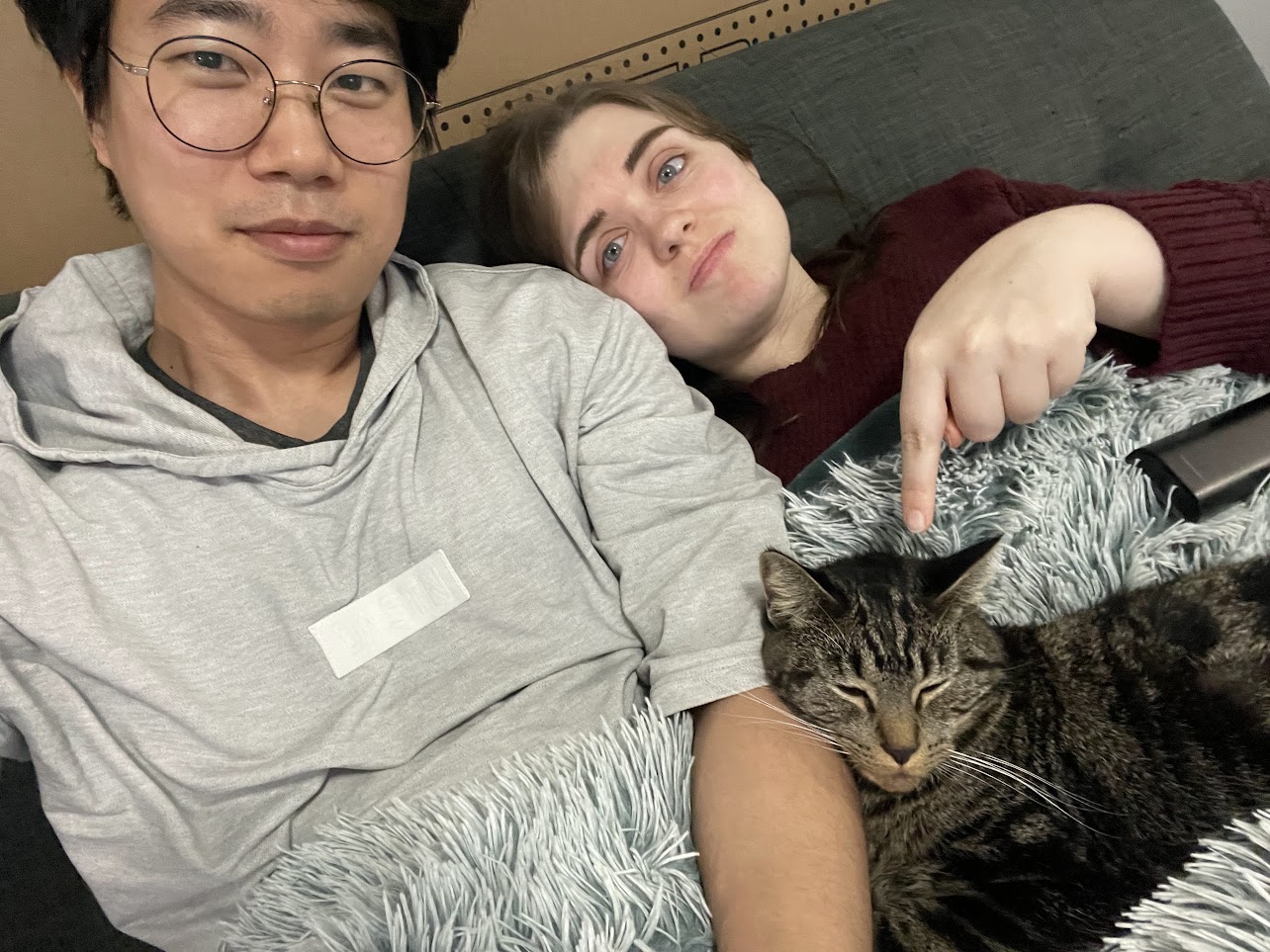 The couple lying down with their cat Cookie