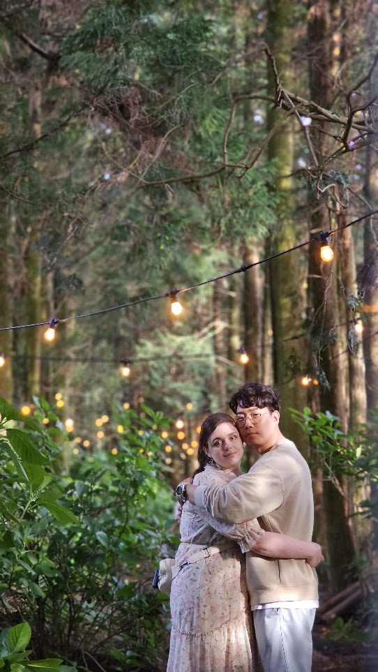 The couple taking a photo together in a forest in Jeju