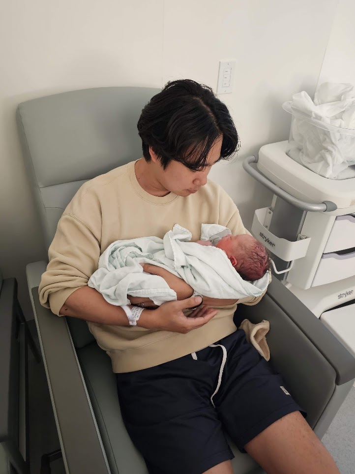 A father holding newborn Youngjoon at the hospital